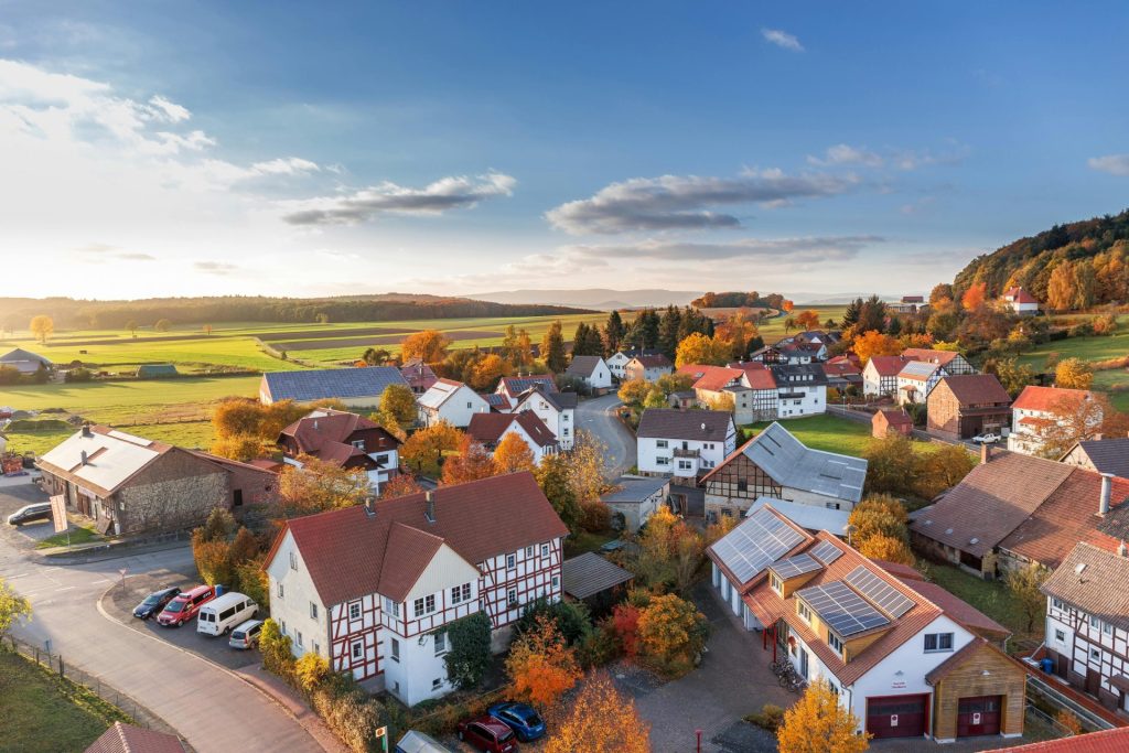 Luftaufnahme eines ländlichen Dorfes im Herbst mit leuchtenden Farben und klarem Himmel
